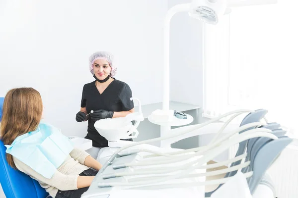 Dental clinic. Reception, examination of the patient. Teeth care. Female dentist in dental office talking with girl patient.