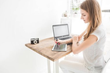 Evde çalışan genç iş kadını ve berabere tablette. Yaratıcı İskandinav tarzı çalışma alanı