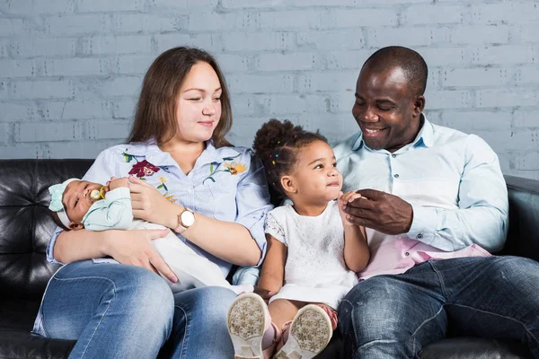 Familia multiétnica feliz sentado en el sofá en el interior moderno — Foto de Stock
