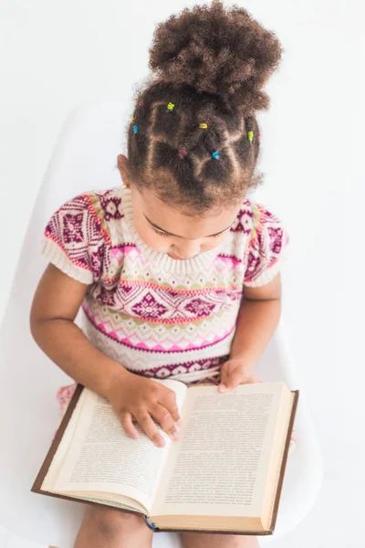 Retrato de una niña con un vestido colorido leyendo un libro sobre un fondo blanco — Foto de Stock