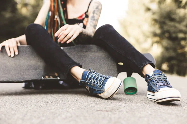 Chica joven con tatuaje y rastas sentado en el parque —  Fotos de Stock