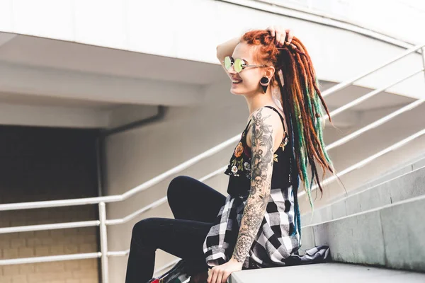 Junges Mädchen mit Tätowierung und Dreadlocks sitzt auf den Stufen — Stockfoto