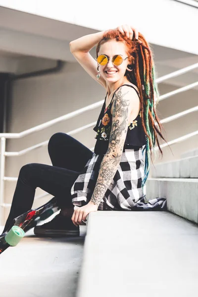 Chica joven con tatuaje y rastas sentado en las escaleras —  Fotos de Stock