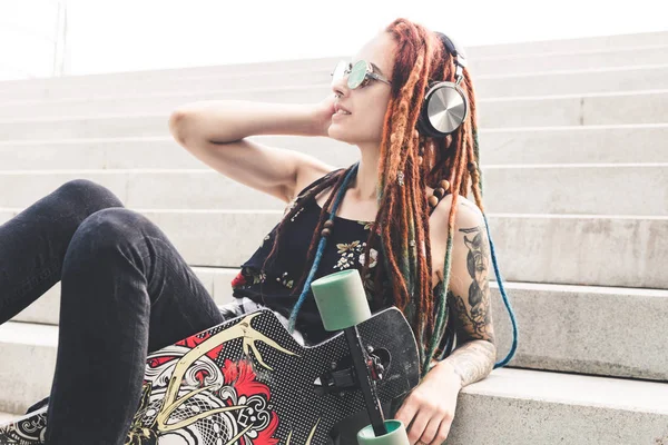 UFA, RÚSSIA - 12 de setembro de 2018 Foto editorial de uma jovem com tatuagem e dreadlocks ouvindo música enquanto se senta nos degraus — Fotografia de Stock