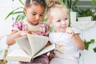 İki küçük kız tencere bitkiler arka plan üzerine bir kitap okumak