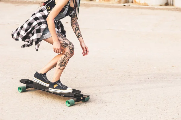 Chica joven con tatuajes paseos en un longboard — Foto de Stock