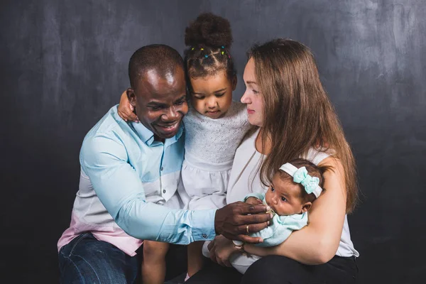 Retrato de una familia internacional con dos hijos sobre un fondo negro — Foto de Stock