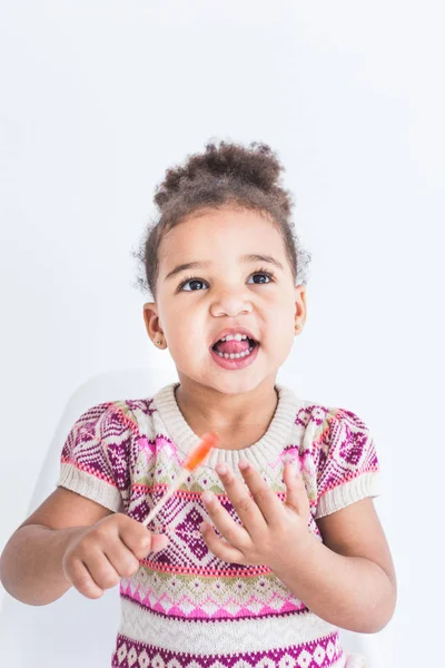 Retrato de una niña en un vestido colorido con una piruleta sobre un fondo blanco — Foto de Stock