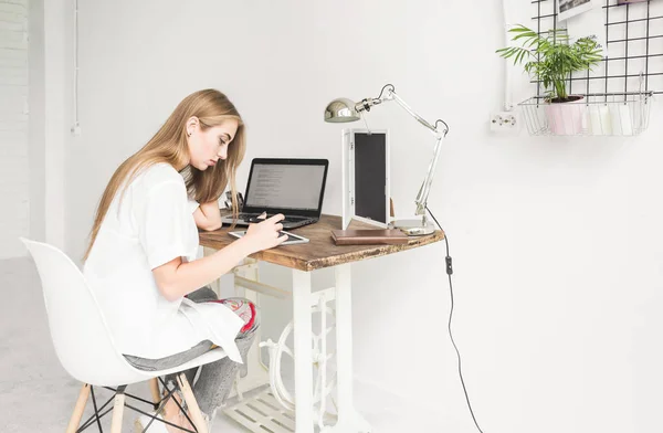 Молодий ділової жінки працювати вдома позаду ноутбука і планшета. Творчі скандинавському стилі робочої області — стокове фото
