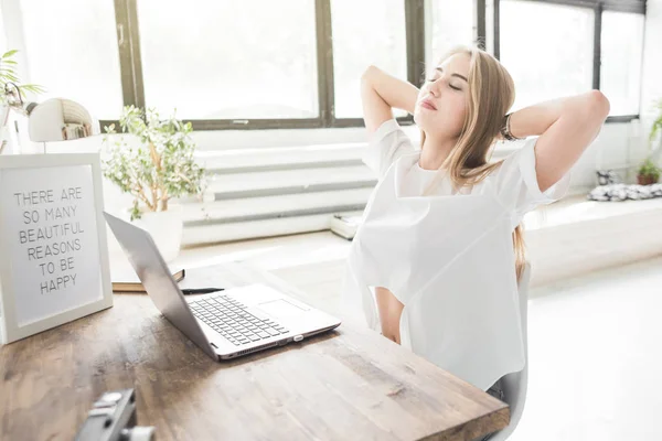 Jonge zakenvrouw thuis werken achter een laptop en haar handen te strekken. Creatieve Scandinavische stijl werkruimte — Stockfoto