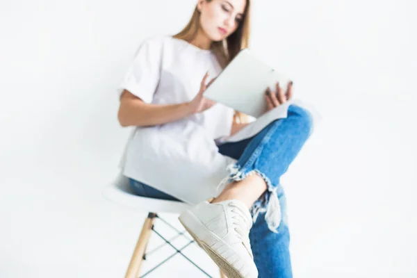 Портрет молодої стильної блондинки в білій футболці і блакитних джинсах, використовуючи планшет на білому тлі — стокове фото