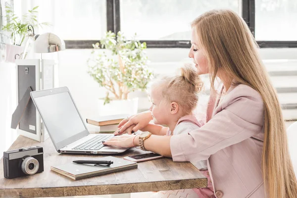 Joven mujer de negocios que trabaja en casa detrás del portátil con un niño pequeño. Espacio de trabajo de estilo escandinavo creativo. Trabajos sobre el permiso de maternidad — Foto de Stock