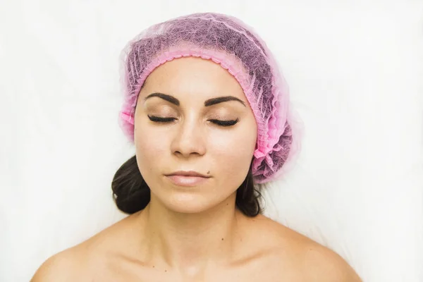 A patient woman with closed eyes lies in the doctors office. Cosmetic procedures in cosmetology office. Face of the patient close-up — Stock Photo, Image