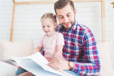 Baba ve kızı birlikte oturup kitap okumak.