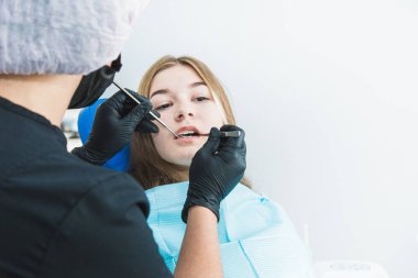 Diş sağlığı kliniği. Resepsiyon, hastanın muayenesi. Diş bakımı. Genç kız bir diş hekimi tarafından muayene ediliyor.