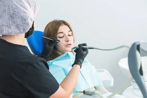 Clínica dental. Recepción, examen del paciente. Cuidado de los dientes. Dentista curando a una paciente chica — Foto de Stock