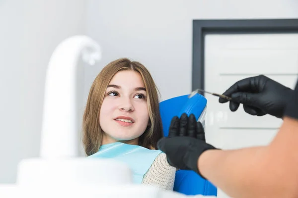 Dental clinic. Reception, examination of the patient. Teeth care. Female dentist in dental office talking with girl patient.