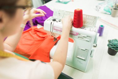 Dikiş atölyesi. Terzi iş başında. Dikiş makinesi ile çalışan genç kadın.