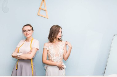 Dikiş atölyesi. Terzi iş başında. Terzi bir gelinlik ölçümleri alır