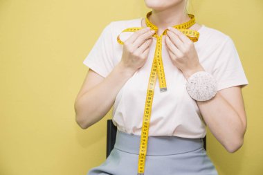 Dikiş atölyesi. Terzi iş başında. Renkli bir arka plan kasette ölçme ile genç bir terzi portresi.