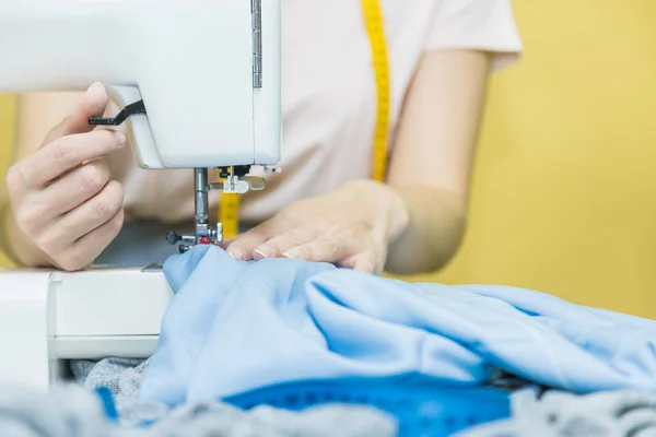 Nähwerkstatt. Näherin bei der Arbeit. junge Frau arbeitet mit Nähmaschine auf farbigem Hintergrund — Stockfoto