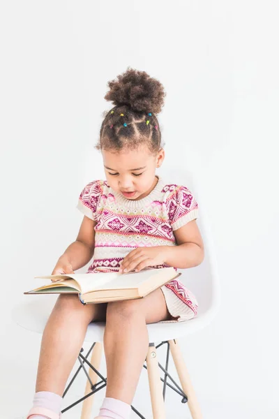 Potret seorang gadis kecil dalam gaun berwarna-warni Membaca buku di latar belakang putih — Stok Foto