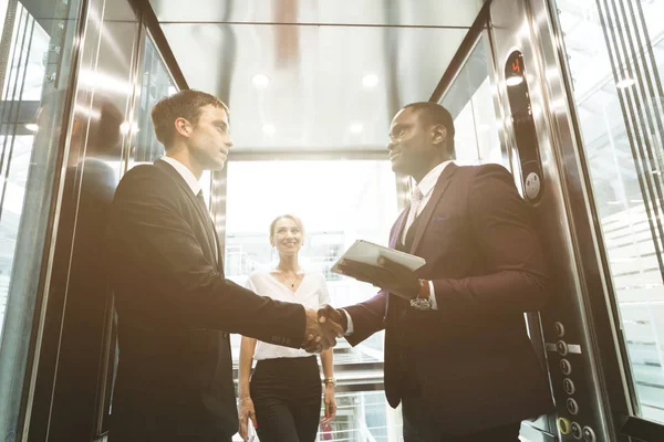 successful and young businessmen in the elevator business center rides to work. business handshake