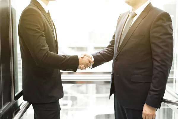 Hombres de negocios jóvenes y exitosos en el centro de negocios de ascensores cabalga al trabajo. apretón de manos — Foto de Stock