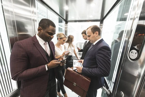 Hombres de negocios jóvenes y exitosos en el centro de negocios de ascensores viaja al trabajo — Foto de Stock