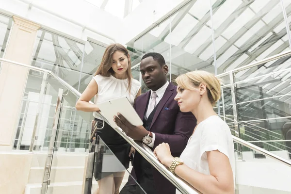 Jóvenes empresarios bajan las escaleras y se comunican. Hombre afroamericano y mujer europea — Foto de Stock