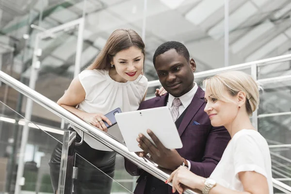 Jóvenes empresarios bajan las escaleras y se comunican. Hombre afroamericano y mujer europea — Foto de Stock