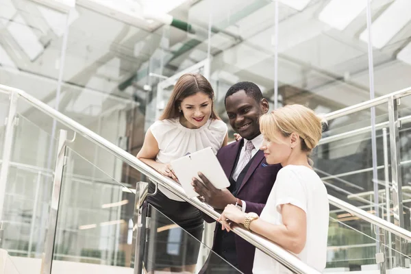 Jóvenes empresarios bajan las escaleras y se comunican. Hombre afroamericano y mujer europea — Foto de Stock