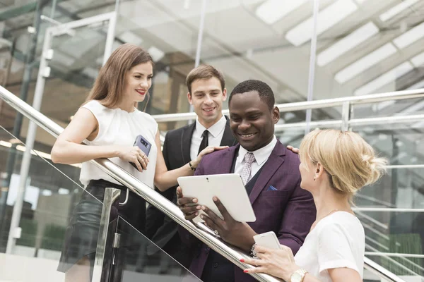 Jóvenes empresarios bajan las escaleras y se comunican. Hombre afroamericano y mujer europea — Foto de Stock