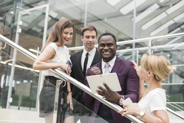 Jóvenes empresarios bajan las escaleras y se comunican. Hombre afroamericano y mujer europea — Foto de Stock