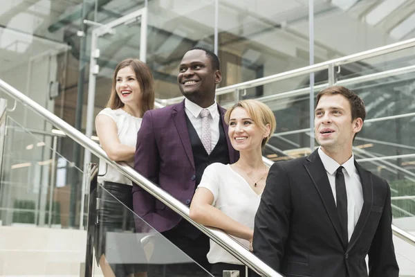 Jóvenes empresarios bajan las escaleras y se comunican. Hombre afroamericano y mujer europea — Foto de Stock