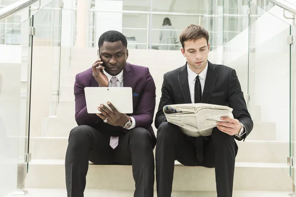 Hombre de negocios maduro usando una tableta digital para discutir información con un colega más joven en un salón de negocios moderno — Foto de Stock