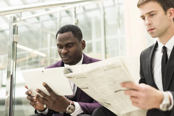 Hombre de negocios maduro usando una tableta digital para discutir información con un colega más joven en un salón de negocios moderno — Foto de Stock