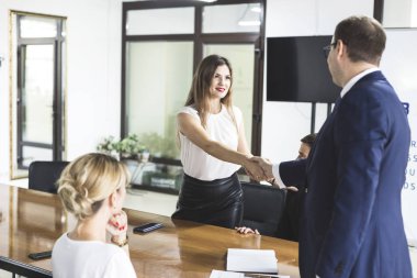 Modern ofis çok ırklı genç yaratıcı insanlar. Grup Genç iş adamları dizüstü bilgisayar, tablet, akıllı telefon, Not defteri ile birlikte çalışıyoruz. el sıkışma