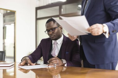 Afrikalı Amerikalı adam kontrat imzalıyor, siyahi adam resmi belgeye imza atıyor, çift ırklı müşteriler evlilik öncesi anlaşma konseptini satın alıyor veya imzalıyor.