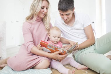 Gülümseyen mutlu genç annesi ve babası evde onların oturma odasında sevgiyle ayakta kollarını şirin bebek kız kucaklarken