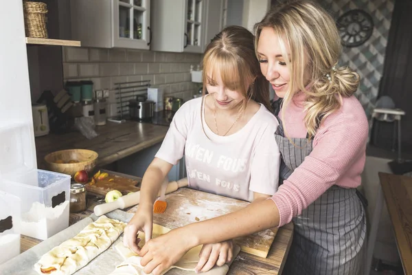 happy family is preparing a pie in the kitchen at home. concept of happy family and home coziness. mother and daughter cooking