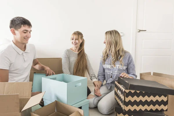 Familia desembalaje cajas de cartón en el nuevo hogar. mudarse a una casa nueva. concepto de una familia feliz y la inauguración de la casa — Foto de Stock