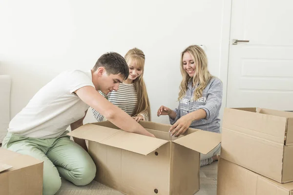 Familia desembalaje cajas de cartón en el nuevo hogar. mudarse a una casa nueva. concepto de una familia feliz y la inauguración de la casa — Foto de Stock