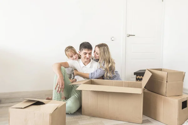 Famiglia disfare scatole di cartone in una nuova casa. trasferirsi in una nuova casa. concetto di una famiglia felice e housewarming — Foto Stock