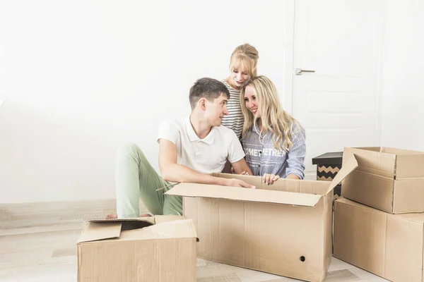 Familia desembalaje cajas de cartón en el nuevo hogar. mudarse a una casa nueva. concepto de una familia feliz y la inauguración de la casa — Foto de Stock