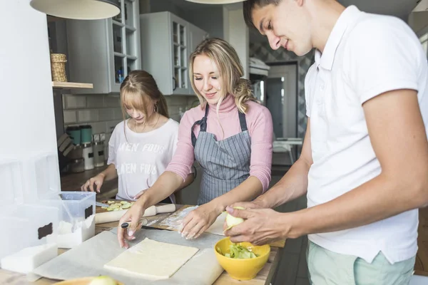 Familia feliz está preparando un pastel en la cocina en casa. concepto de familia feliz y acogedor hogar — Foto de Stock