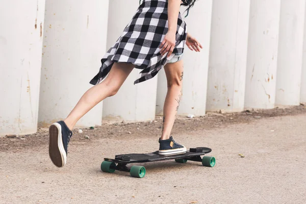 Chica joven con tatuajes paseos en un longboard —  Fotos de Stock