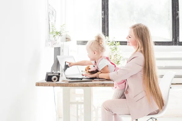 Joven mujer de negocios que trabaja en casa detrás del portátil con un niño pequeño. Espacio de trabajo de estilo escandinavo creativo. Trabajos sobre el permiso de maternidad — Foto de Stock