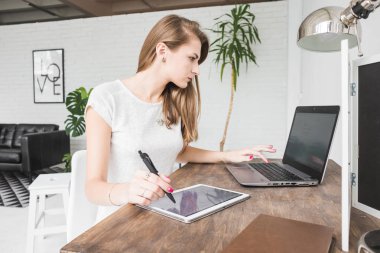 Evde çalışan genç iş kadını ve berabere tablette. Yaratıcı İskandinav tarzı çalışma alanı