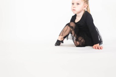 Sevimli küçük kız beyaz zemin katta oturan güzel siyah elbiseli.